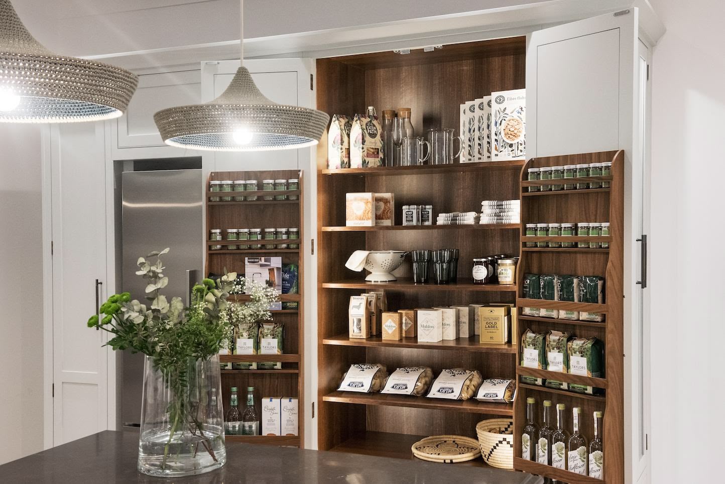 White pantry with dark wood interior open to show organised storage