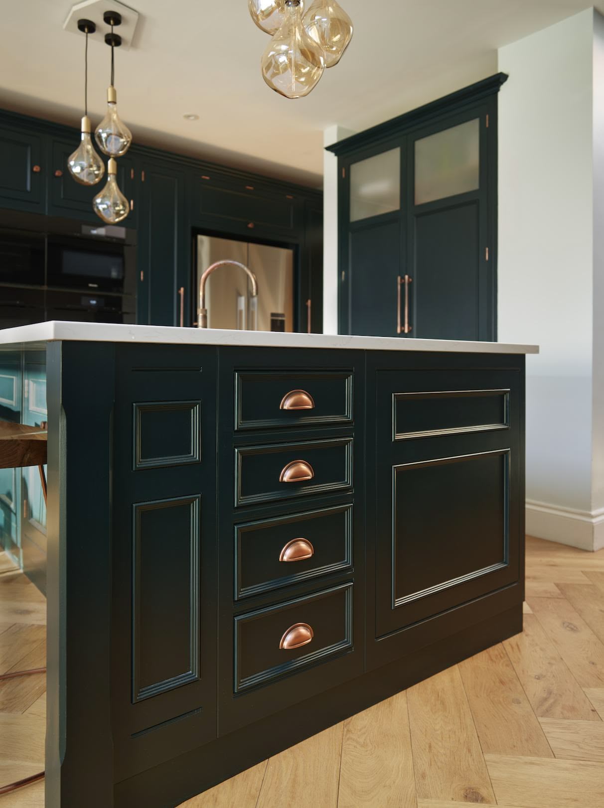 Vibrant green kitchen island with brass handles and white worktop