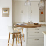 White Shaker kitchen island with round oak extension with white and walnut bar stools