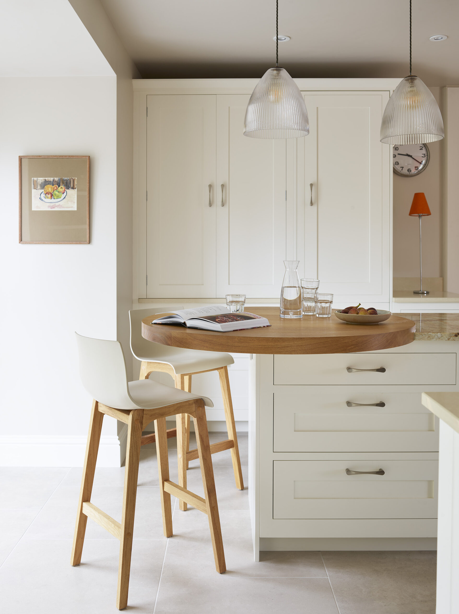 White Shaker kitchen island with round oak extension with white and walnut bar stools