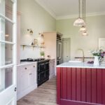 Arbor kitchen design featuring blush pink cabinetry, burgundy kitchen island with white marble worktop and dark flooring