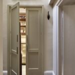 Large beige pantry doors open ajar to reveal organised storage