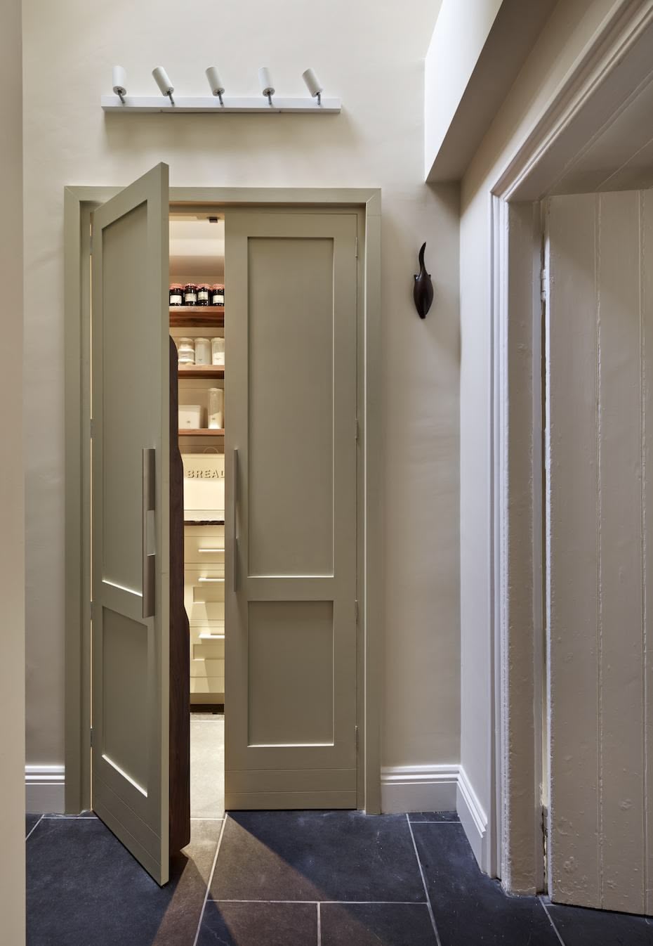 Large beige pantry doors open ajar to reveal organised storage
