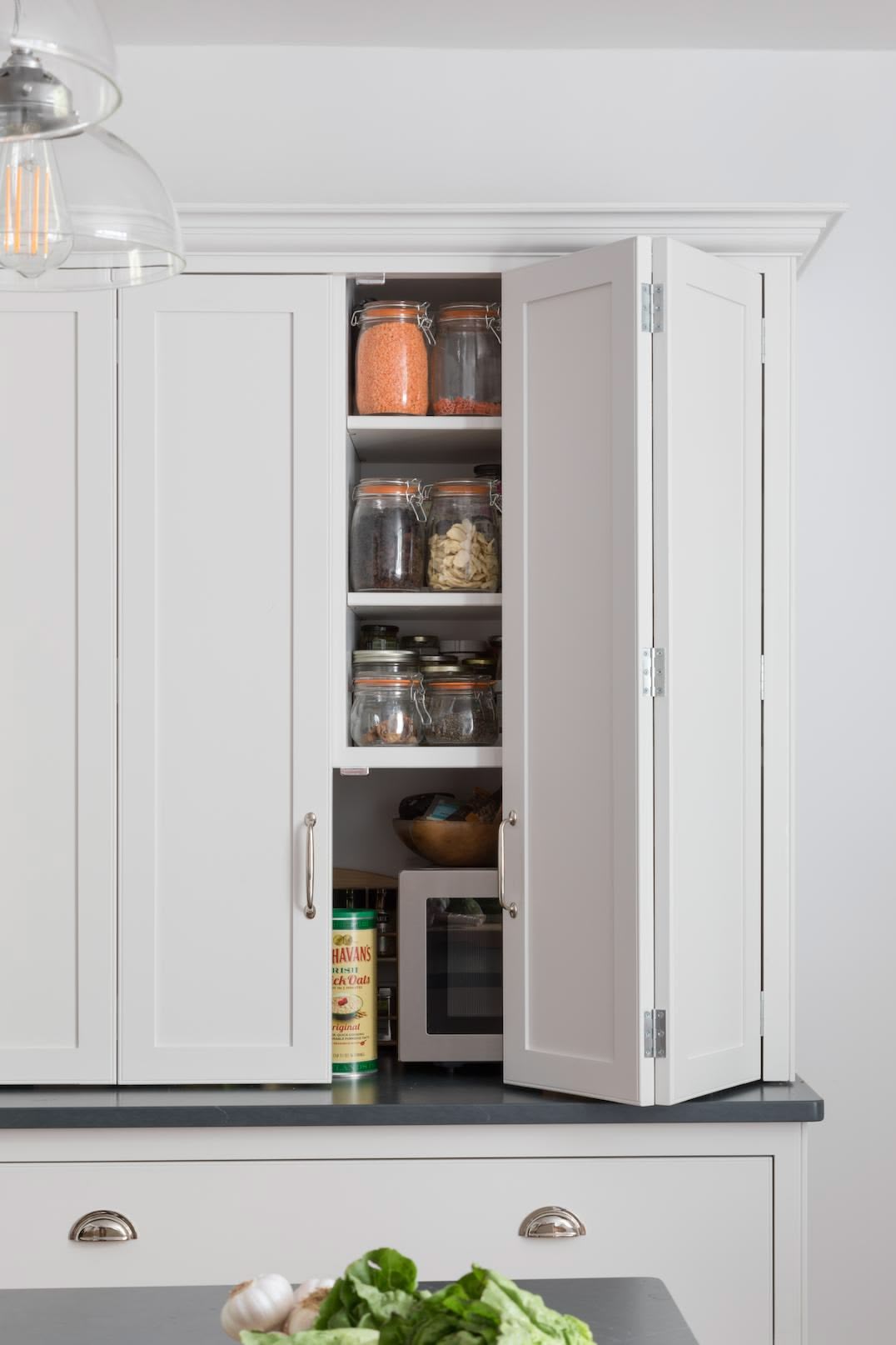 White kitchen cabinet open to show organised shelving