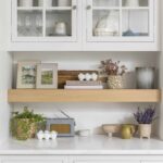 White Original design kitchen cabinetry with overhead glass framed cupboards revealing organised shelving