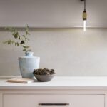 Soft pink Linear kitchen cabinetry with dark brown handles and white worktop