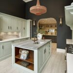 Pale green Arbor kitchen cabinetry against dark walls