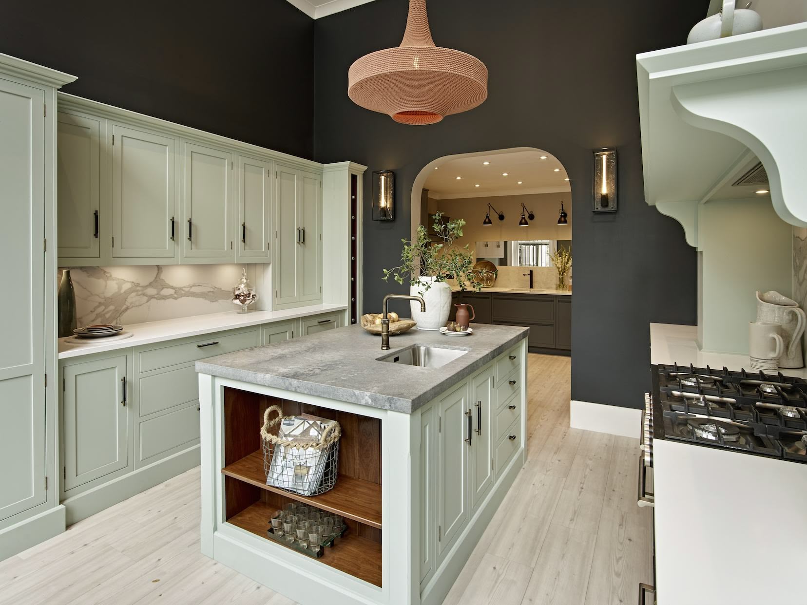 Pale green Arbor kitchen cabinetry against dark walls