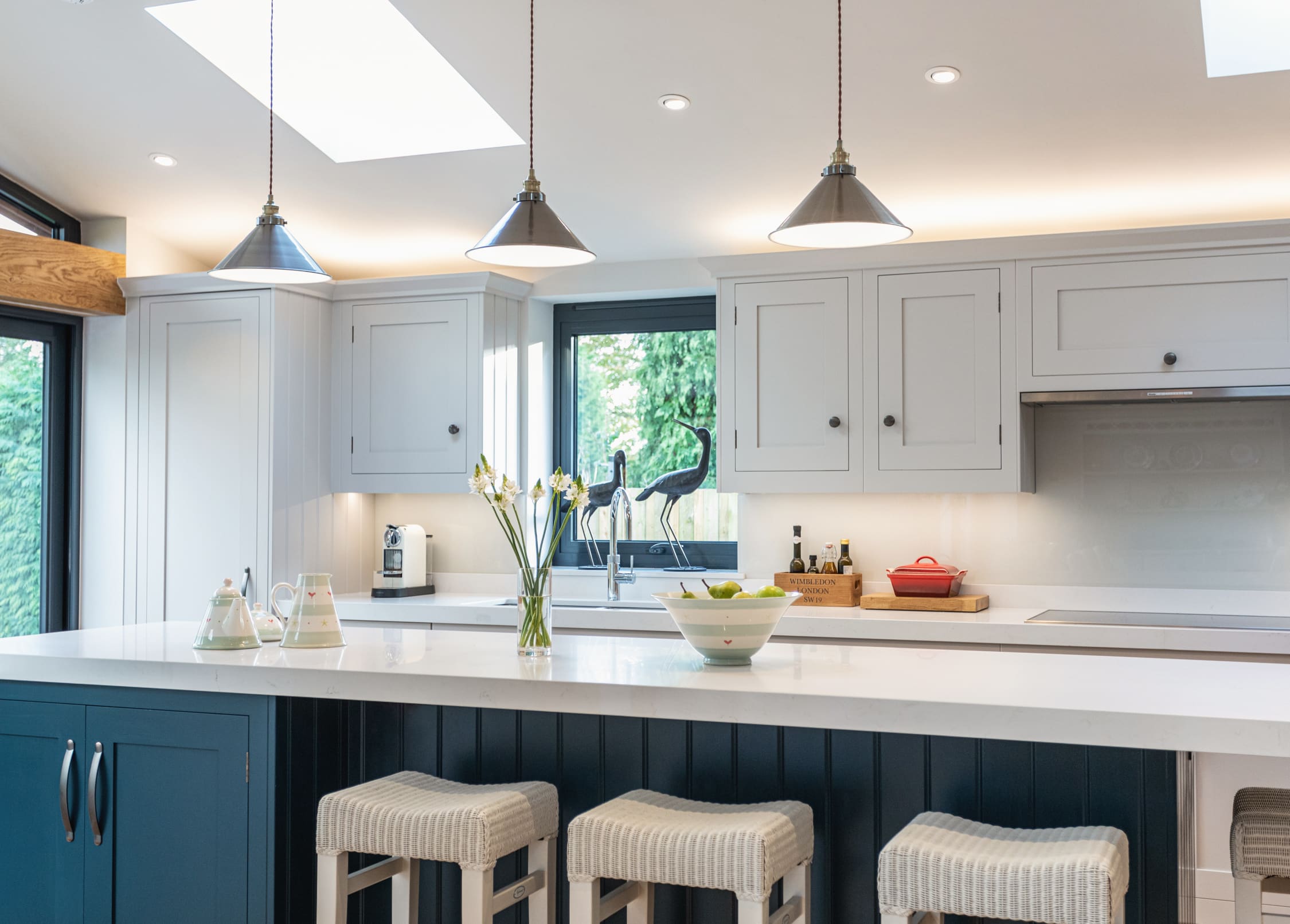 Blue Shaker kitchen island with white worktop and white bar stools