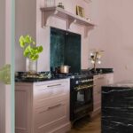 Pink Original kitchen cabinetry with black worktops against pink walls