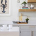 Oak open shelving above grey kitchen cabinetry with white worktop