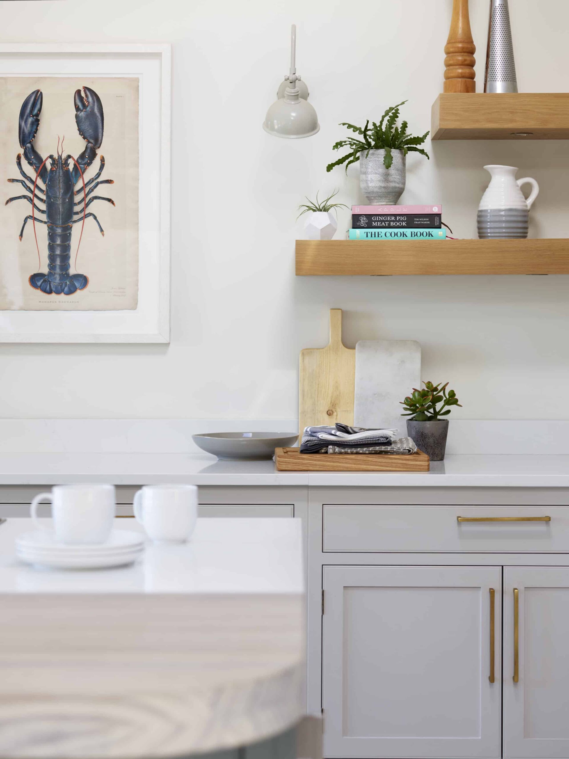 Oak open shelving above grey kitchen cabinetry with white worktop