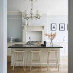 Off-white Original kitchen cabinetry and kitchen island with black worktop featuring natural wooden smile stools