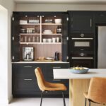 Large dark Shaker kitchen unit open to show hidden workspace and organised shelving
