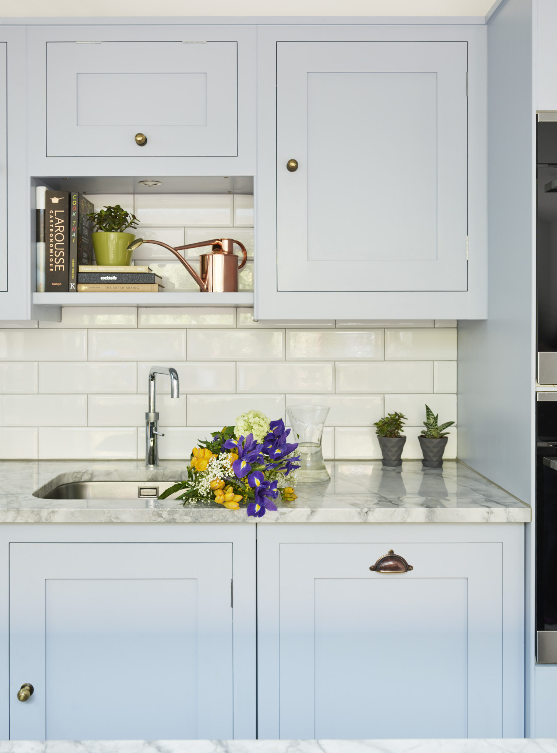 Pale blue Shaker kitchen cabinetry with white marble worktop