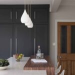 Dark kitchen pantry cabinetry against a white kitchen island with dark oak extension
