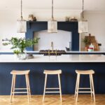 Deep blue kitchen island with white worktop featuring wooden stools