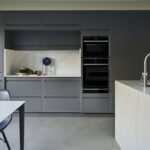 Grey Linear Edge kitchen cabinetry with white marble island and open plan dining area