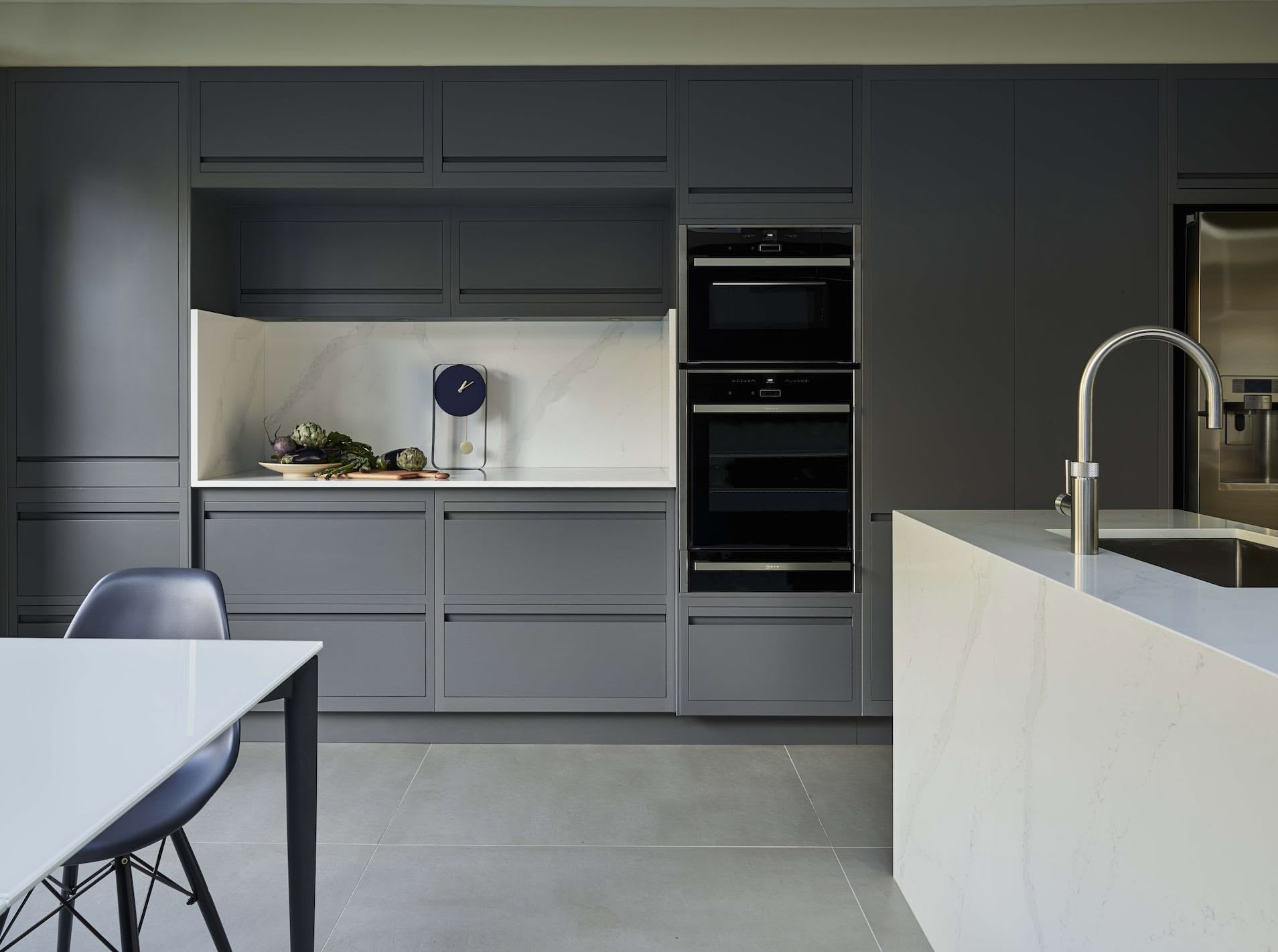 Grey Linear Edge kitchen cabinetry with white marble island and open plan dining area