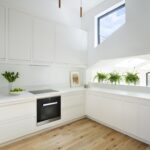 White Linear Edge kitchen cabinetry and worktops with natural wood flooring