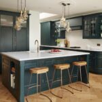 Vibrant green kitchen island with white worktop and oak bar stools in front of vibrant green kitchen cabinetry