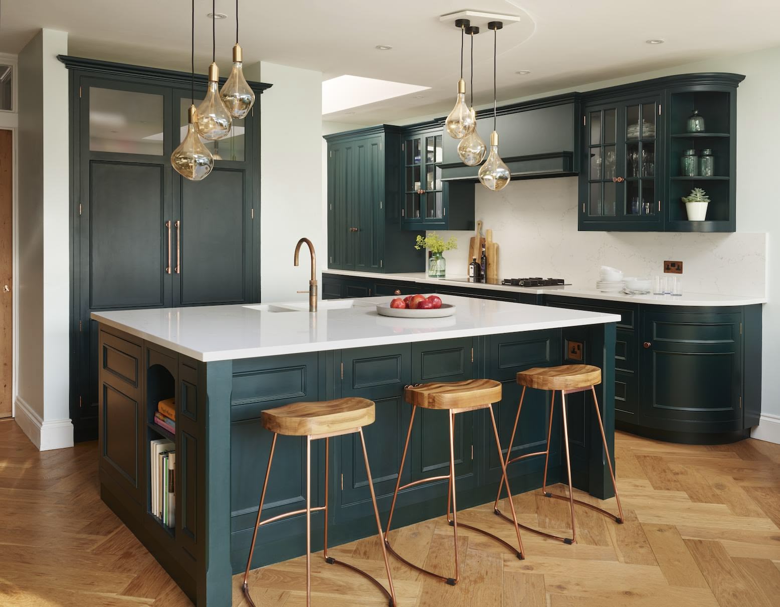 Vibrant green kitchen island with white worktop and oak bar stools in front of vibrant green kitchen cabinetry