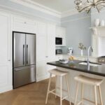 Off-white tall kitchen cabinetry around silver American style fridge