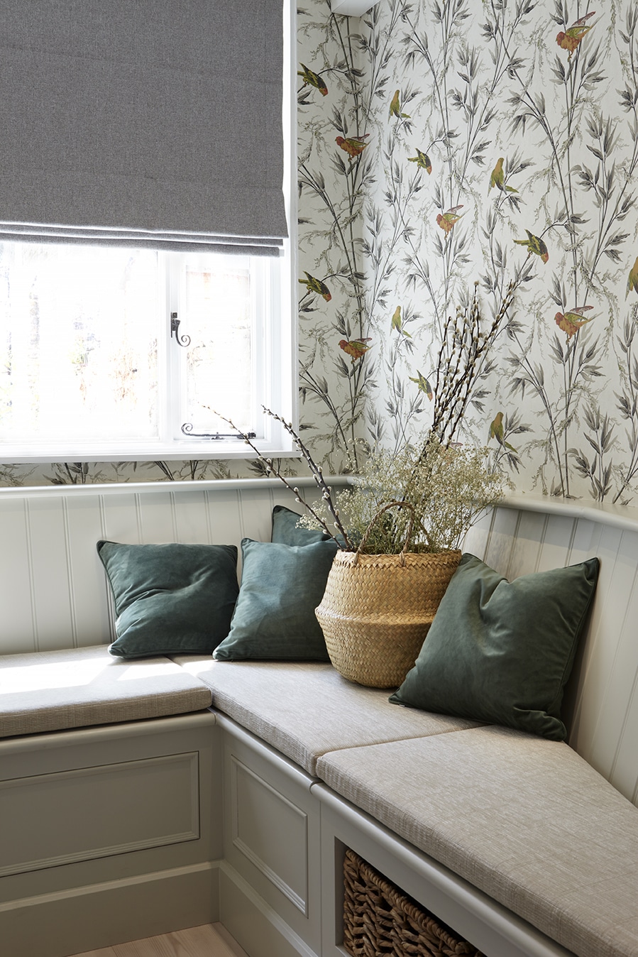 Grey corner bench seating area against a window with green cushions