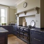 Black Shaker kitchen cabinetry and marble worktop with beige cooker alcove