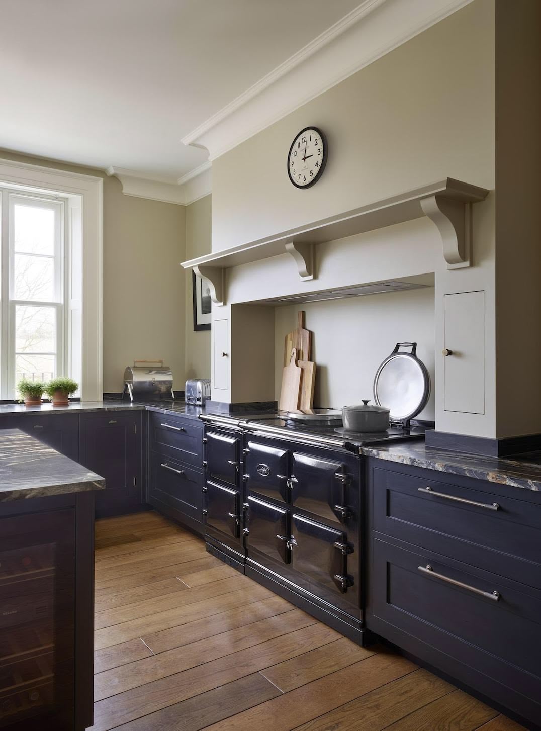 Black Shaker kitchen cabinetry and marble worktop with beige cooker alcove