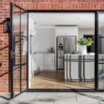 External view of bright Shaker kitchen seen through open glass slider doors