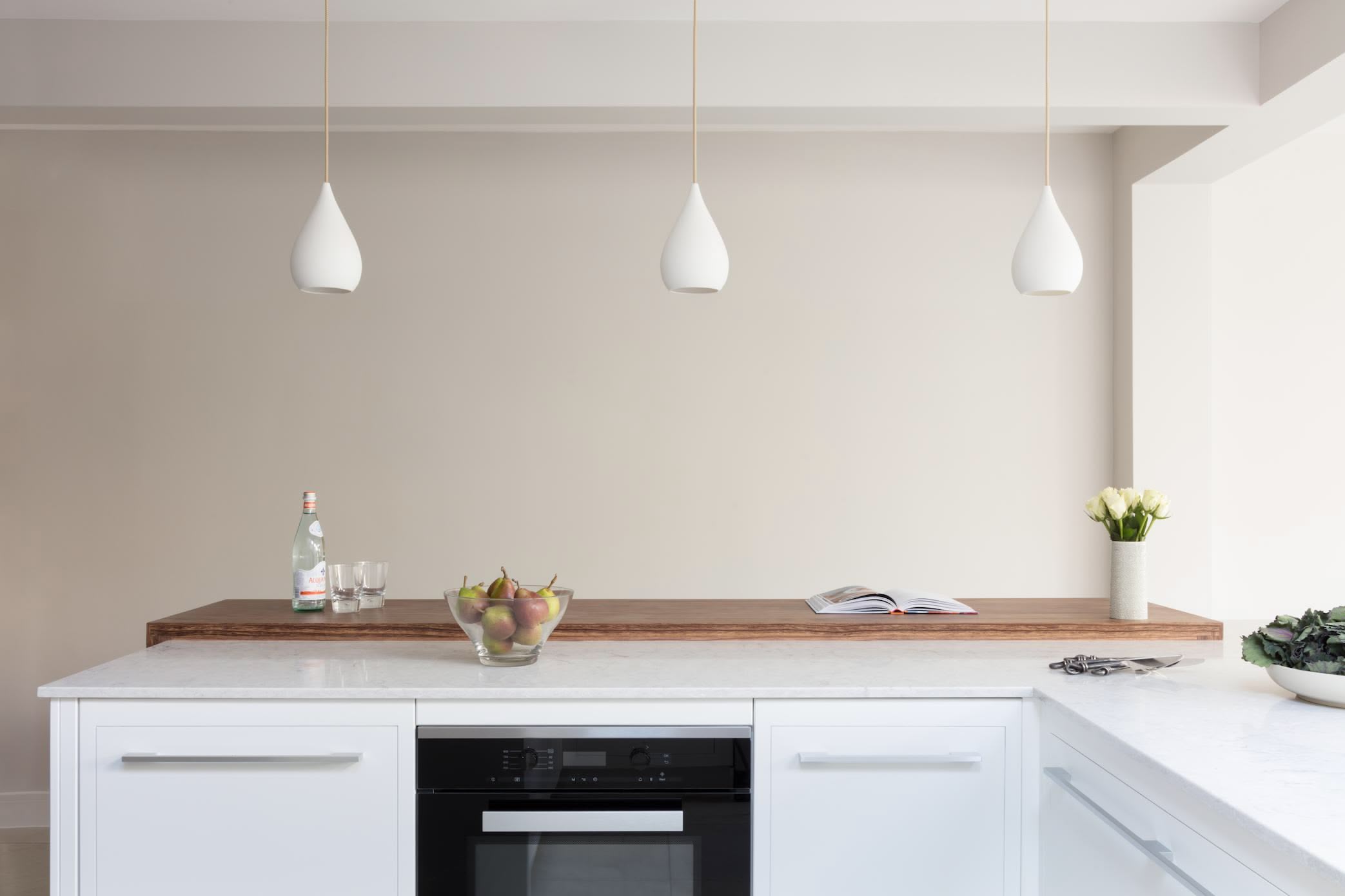 White Linear kitchen island featuring oven and white worktop with dark oak extension