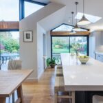 White Shaker kitchen cabinetry with white worktops and open plan dining area