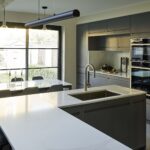 Large grey kitchen island with integrated sink and white marble worktop