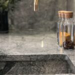 Closeup of green-grey marble worktop and sink with brass tap