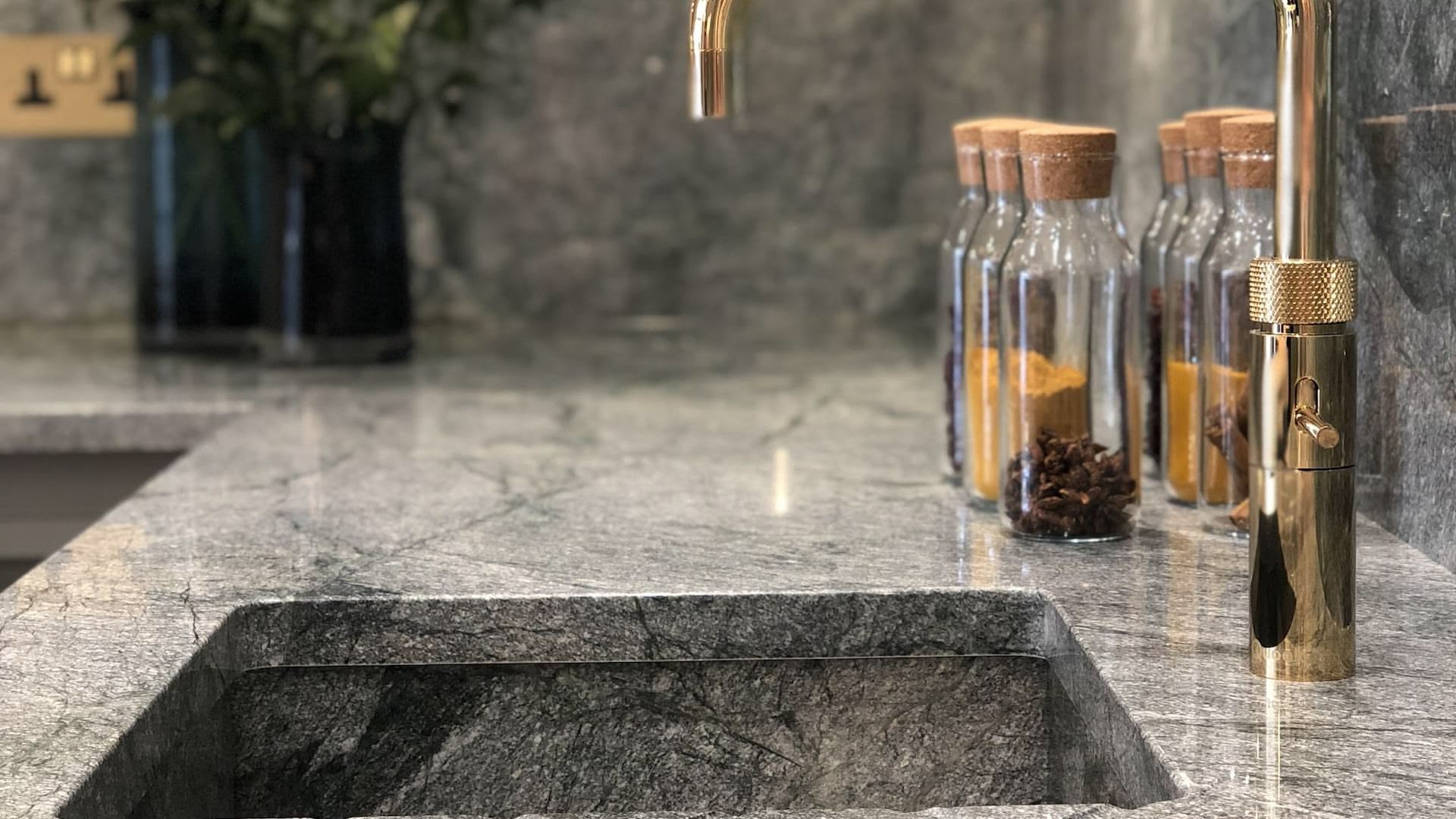 Closeup of green-grey marble worktop and sink with brass tap