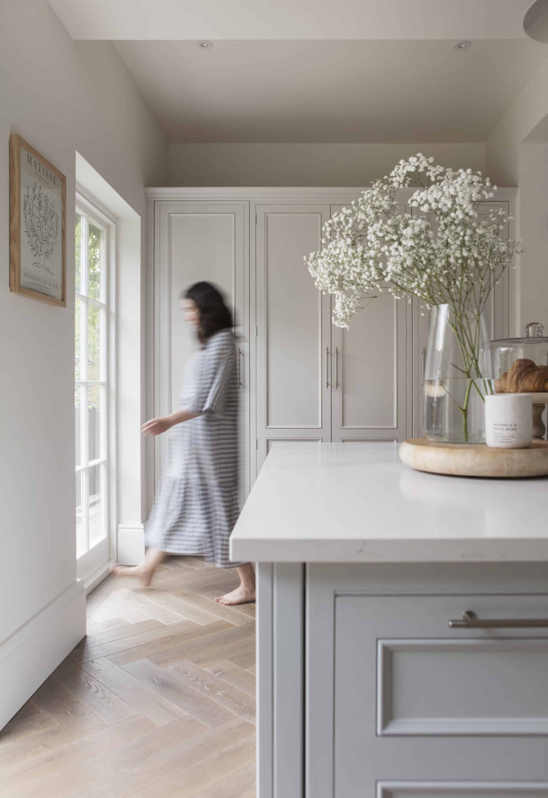 Soft grey kitchen island with silver handles and white worktop