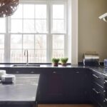 Black Shaker kitchen cabinetry and marble worktop with beige cooker alcove