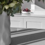 White kitchen island worktop with potted plant overlooking white Shaker kitchen cabinetry