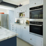 Pale blue Shaker kitchen cabinetry with white marble worktop and integrated appliances
