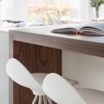 Closeup of dark oak kitchen island extension with white stools