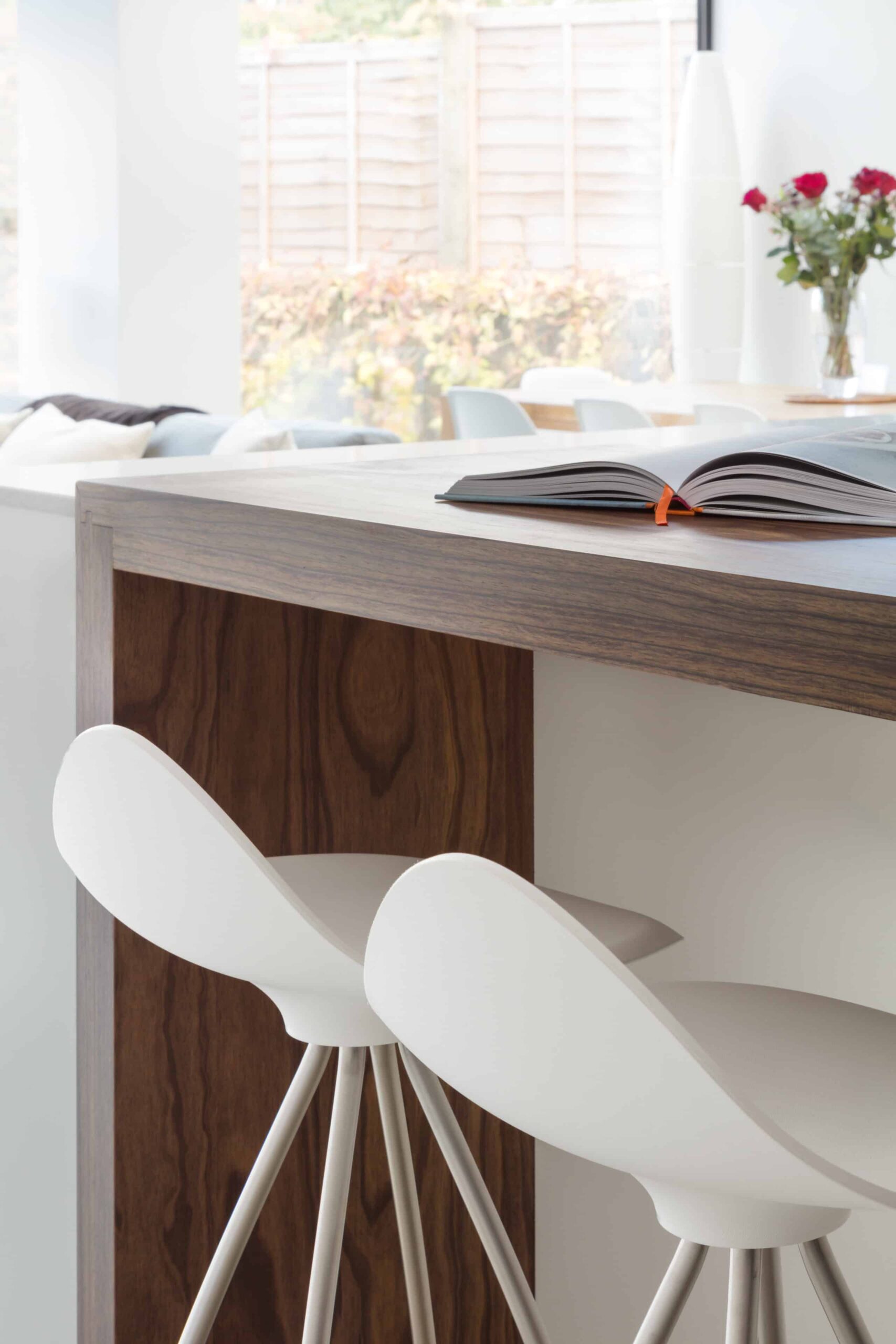 Closeup of dark oak kitchen island extension with white stools