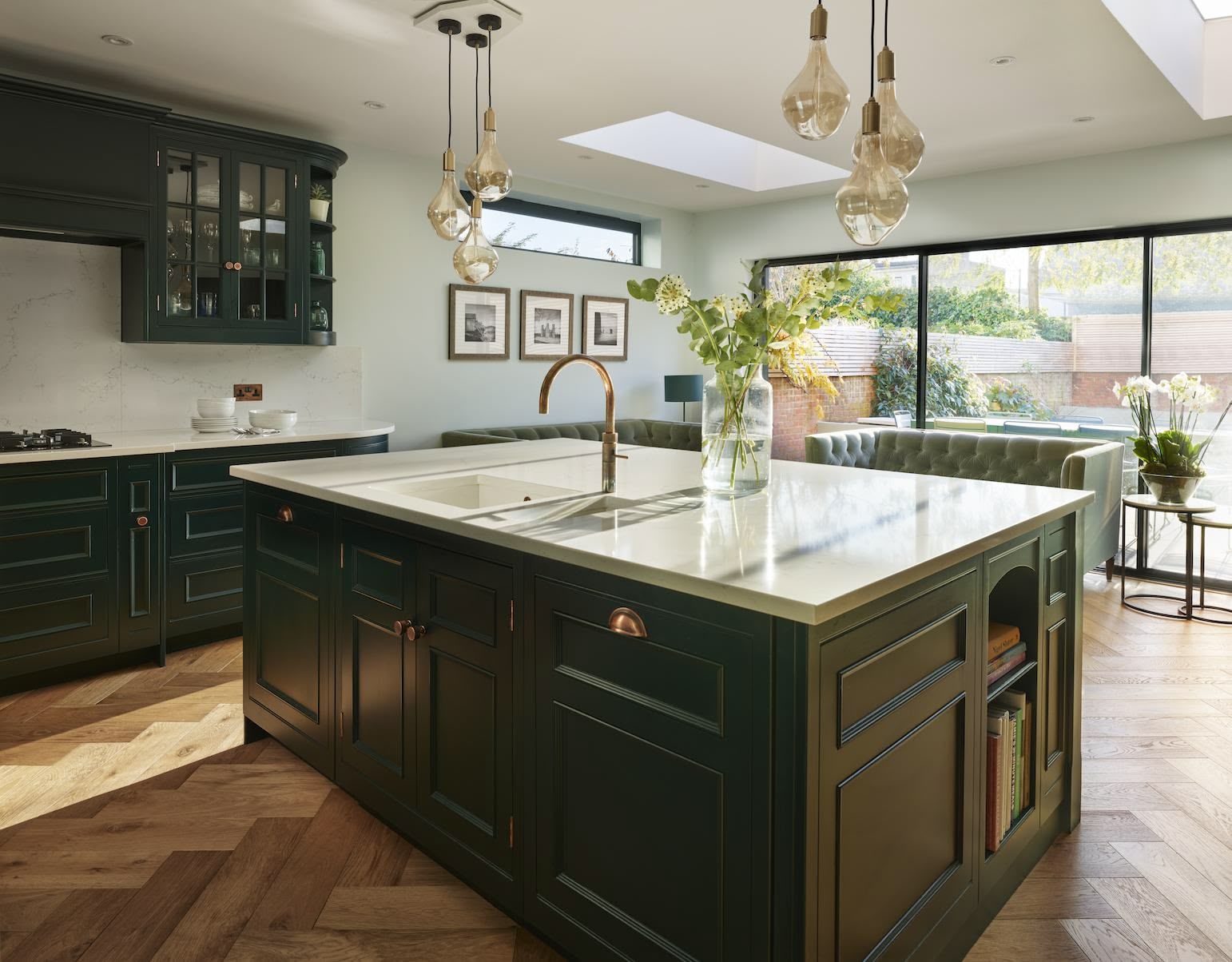 Vibrant green kitchen island with white worktop in front of open plan living area and large windows