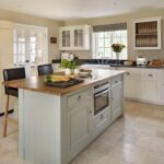 Green-grey kitchen island with walnut worktop against white Original kitchen cabinetry with black worktops