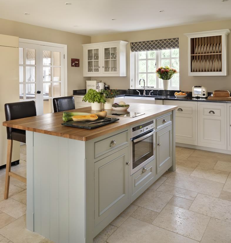 Green-grey kitchen island with walnut worktop against white Original kitchen cabinetry with black worktops