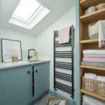 Pale blue utility room cabinetry showing organised shelving and sink