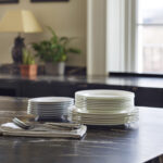 Closeup of black marble worktop with stacked cut crockery