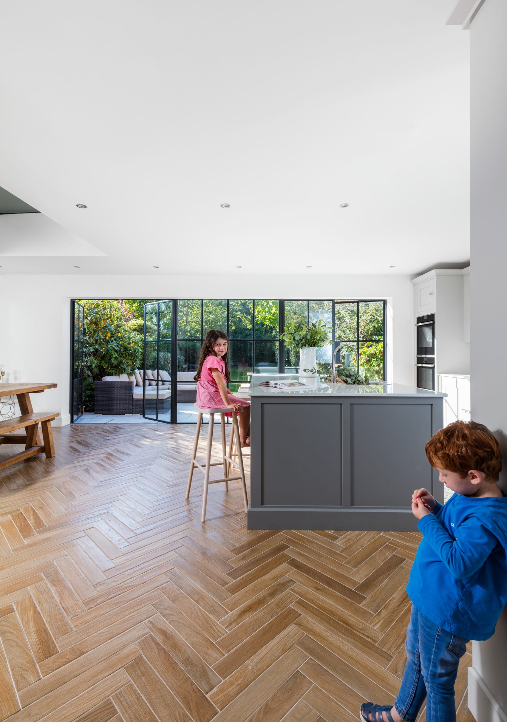 Children situated in bright Shaker kitchen