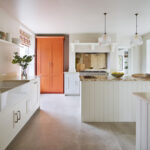 White kitchen cabinetry featuring cream worktops and orange painted pantry
