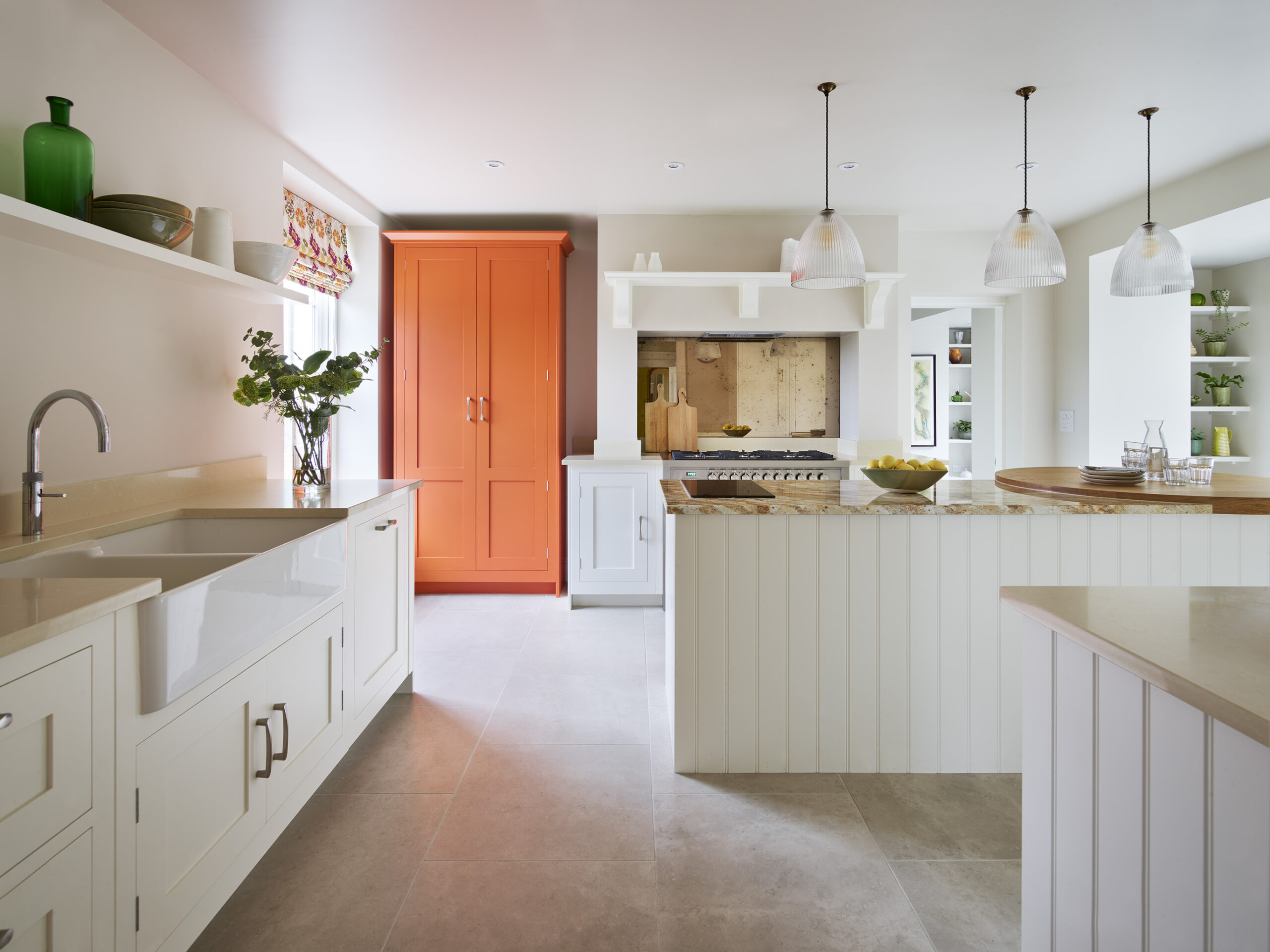 White kitchen cabinetry featuring cream worktops and orange painted pantry